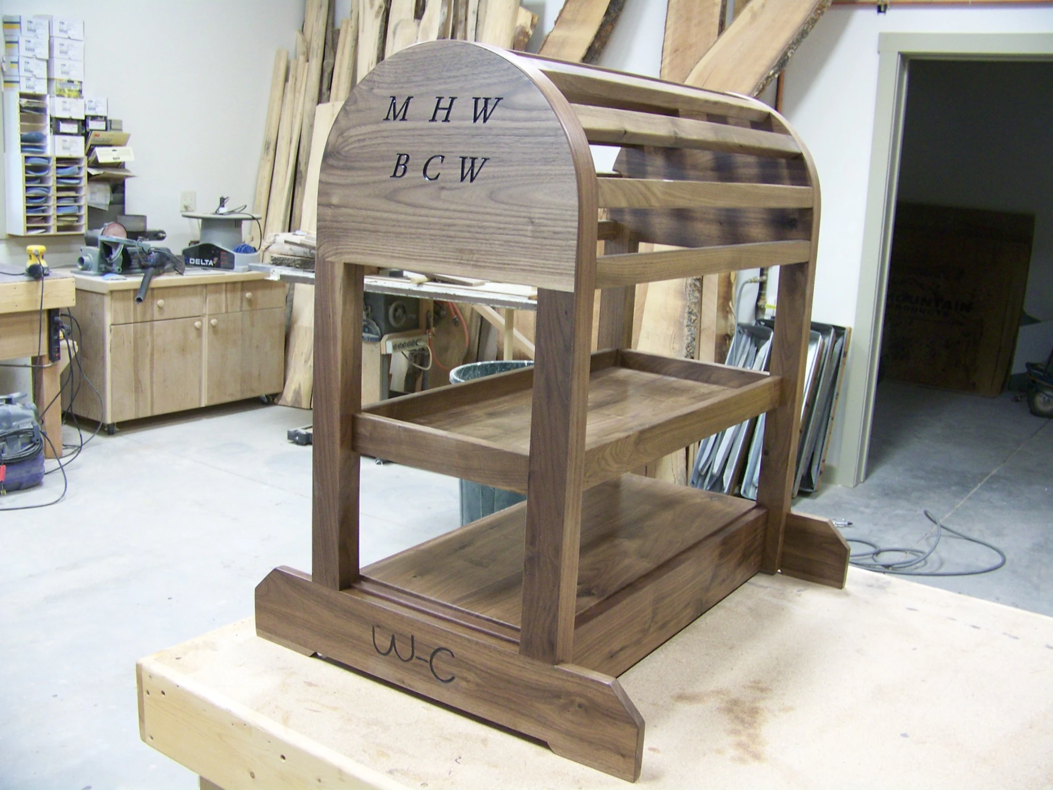 Handcrafted wooden rack with curved upper panels and shelves in the workshop